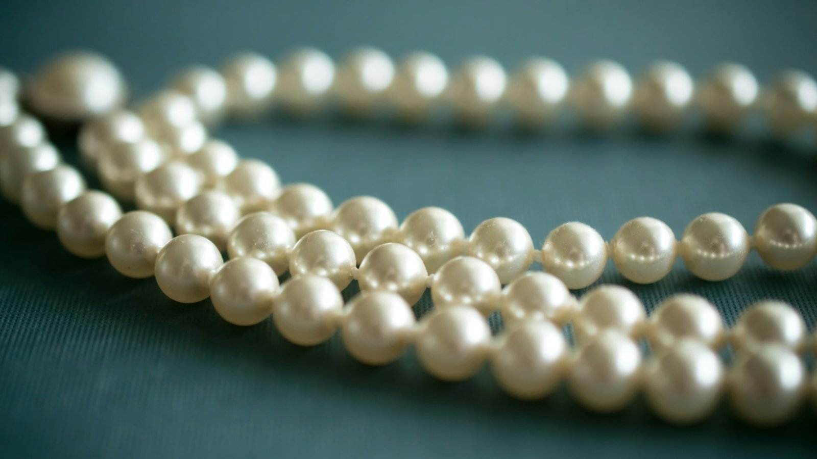 white pearl necklace on gray textile